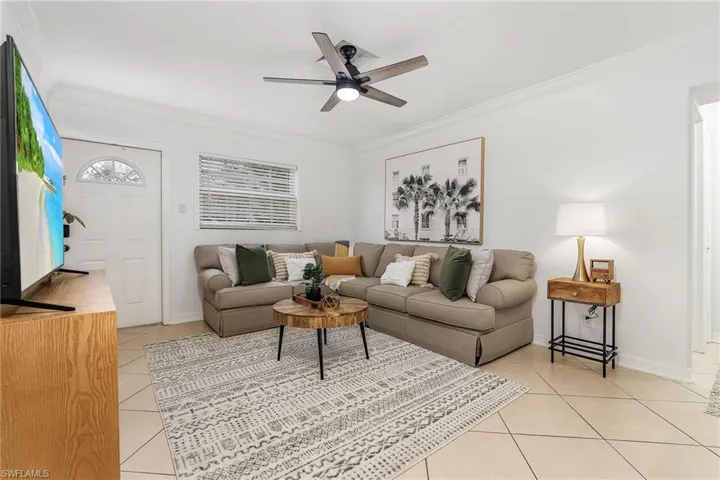 Living area with crown molding, light tile patterned floors, and ceiling fan