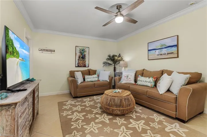 Living area featuring light tile patterned floors, a ceiling fan, and ornamental molding