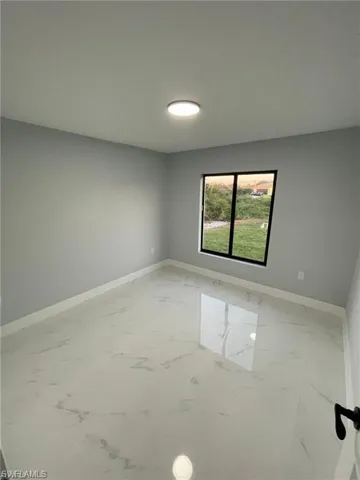Empty room featuring light marble finish flooring and baseboards