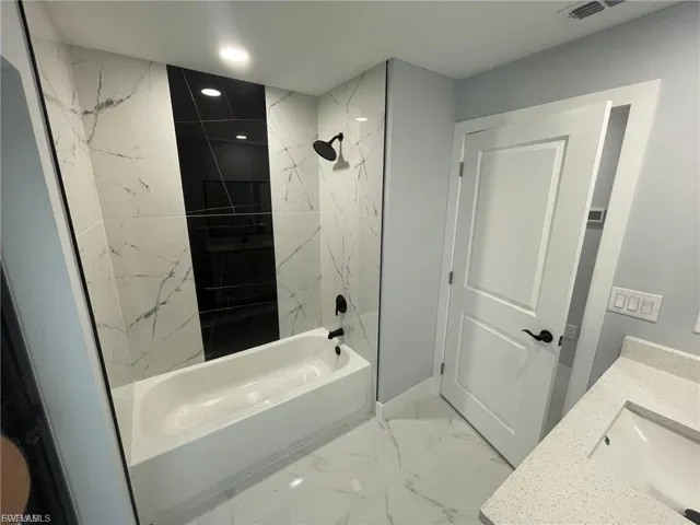 Bathroom featuring shower / washtub combination, marble finish flooring, vanity, and recessed lighting