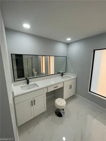Bathroom featuring double vanity, marble finish flooring, and recessed lighting