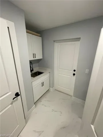 Washroom featuring light marble finish flooring and baseboards