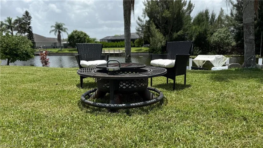 View of grassy yard featuring a fire pit and a water view