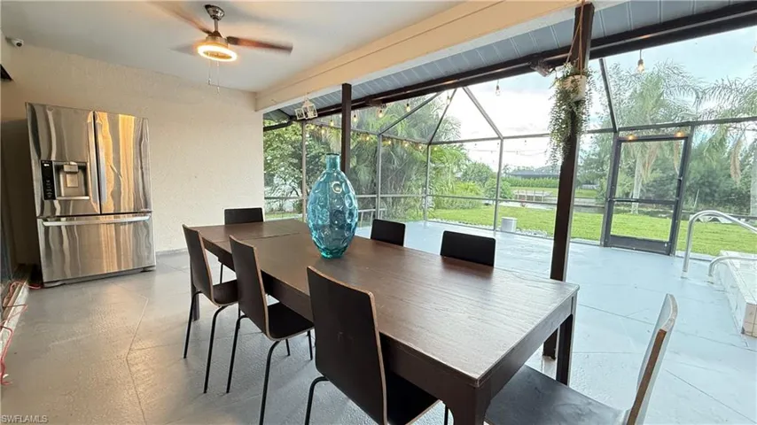 Dining space featuring a ceiling fan, a textured wall, and a sunroom
