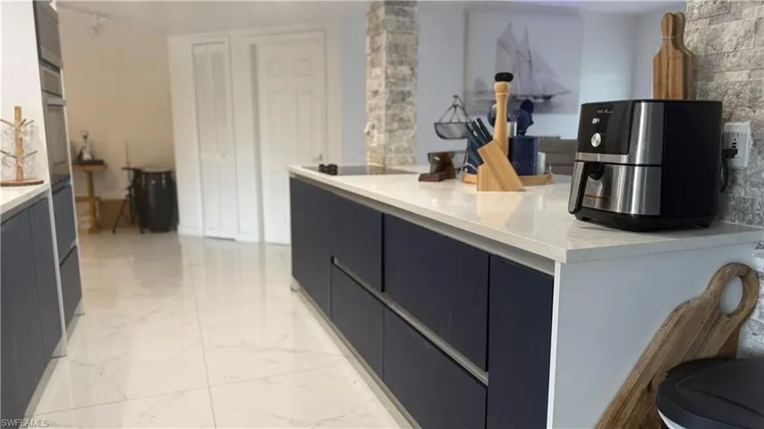 Kitchen with light marble finish floors, light countertops, modern cabinets, white oven, and black electric cooktop