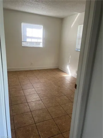 Tiled empty room featuring a textured ceiling