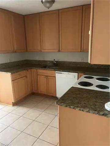 Kitchen with dishwasher, sink, and light tile patterned flooring