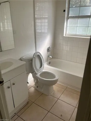 Full bathroom with tile patterned flooring, vanity, toilet, and tiled shower / bath