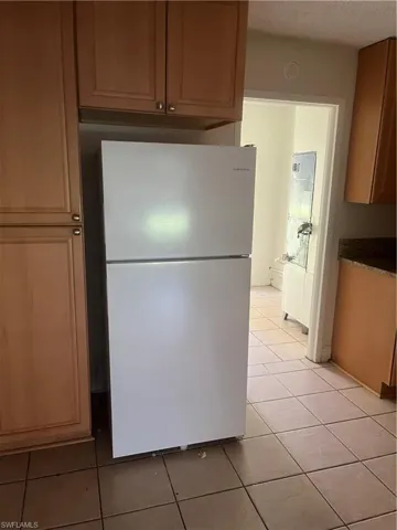 Kitchen featuring light tile patterned flooring, stainless steel refrigerator, and a textured ceiling