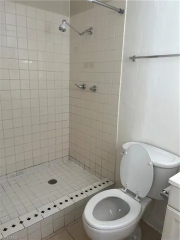 Bathroom featuring vanity, toilet, and a tile shower