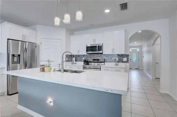 Kitchen with light tile patterned floors, white cabinets, stainless steel appliances, pendant lighting, and recessed lighting