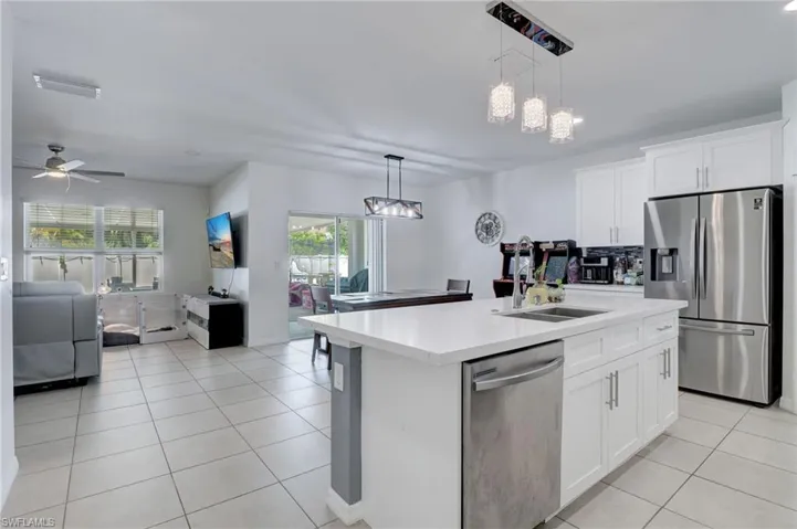 Kitchen featuring open floor plan, stainless steel appliances, white cabinets, a kitchen island with sink, and light tile patterned floors