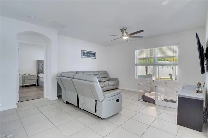 Living area featuring light tile patterned flooring and ceiling fan