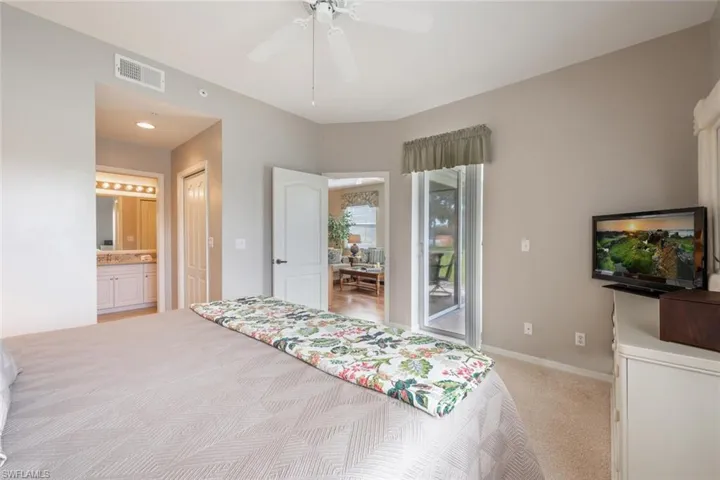 Bedroom featuring connected bathroom, ceiling fan, light colored carpet, and access to exterior