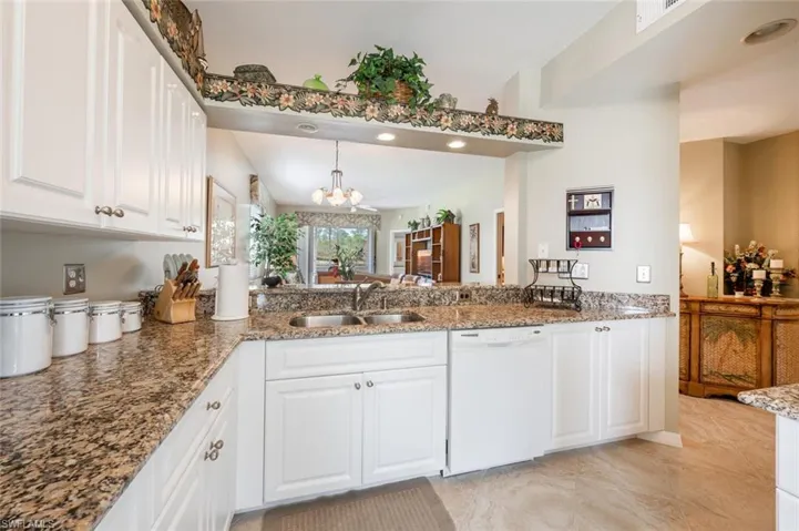 Kitchen with white cabinetry, dishwasher, sink, and hanging light fixtures