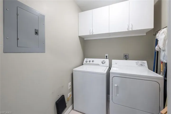 Laundry room with cabinets, independent washer and dryer, and electric panel