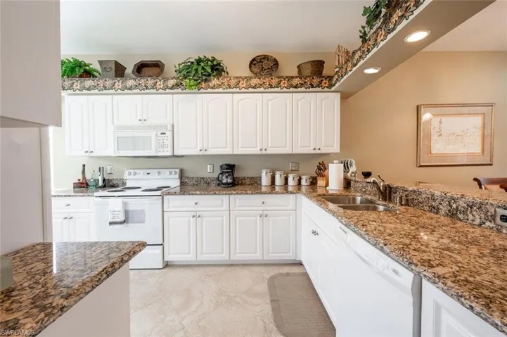 Kitchen with sink, white cabinets, white appliances, and dark stone counters
