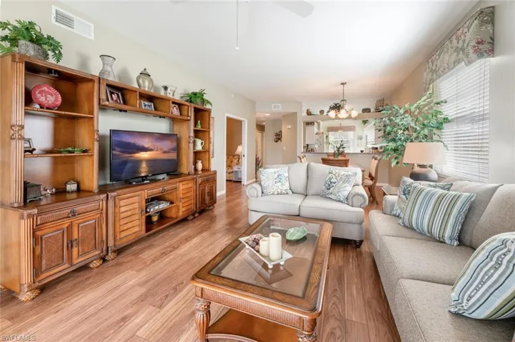Living room featuring light wood-type flooring and ceiling fan with notable chandelier