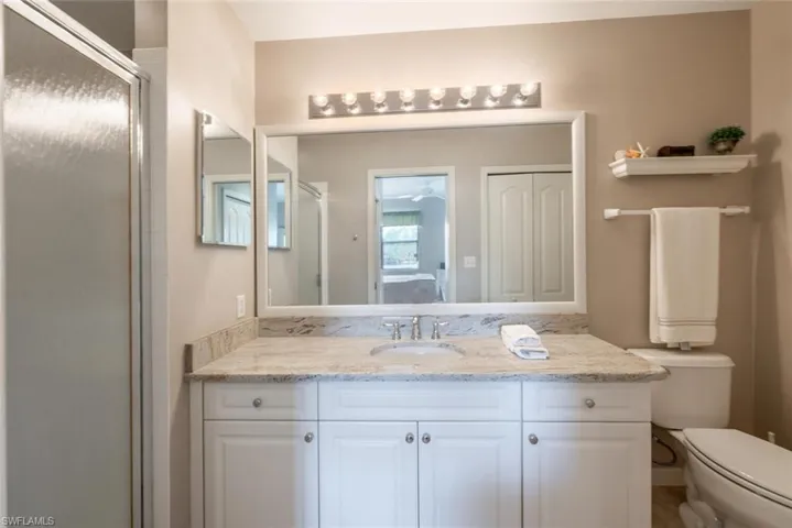 Bathroom featuring vanity, a shower with shower door, and toilet