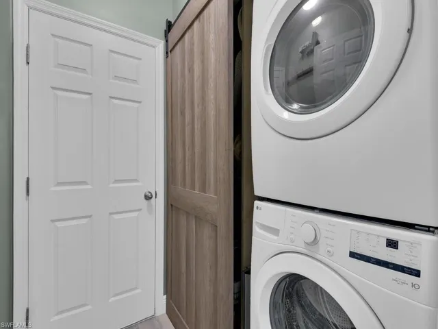 Laundry area featuring a barn door and stacked washer / drying machine