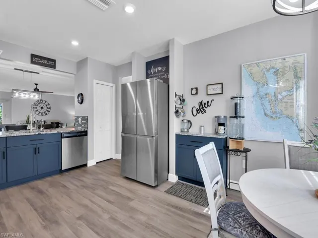 Kitchen featuring blue cabinets, stainless steel appliances, hanging light fixtures, light wood-style floors, and recessed lighting