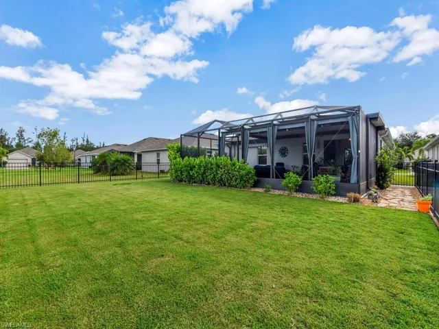 Fenced backyard featuring a sunroom and a lanai