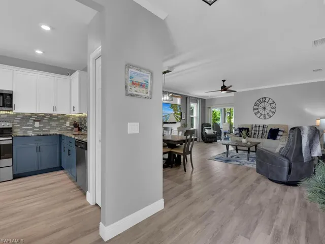 Kitchen with white cabinets, decorative backsplash, appliances with stainless steel finishes, light wood finished floors, and a ceiling fan