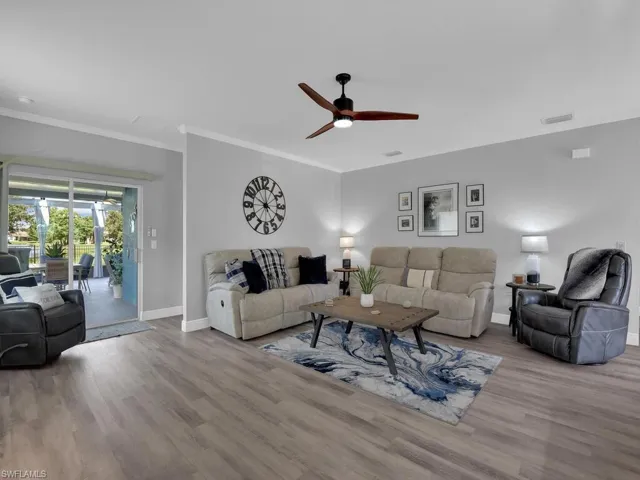 Living room with ceiling fan, wood finished floors, and ornamental molding