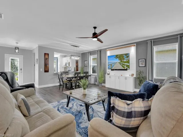 Living room with wood finished floors, ornamental molding, and ceiling fan