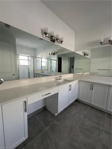 Full bathroom with vanity, a stall shower, and dark tile patterned floors