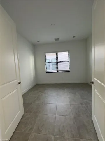 Spare room with baseboards and light tile patterned flooring