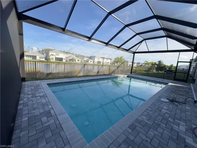 View of pool with a lanai, a residential view, a sunroom, a patio, and a water view