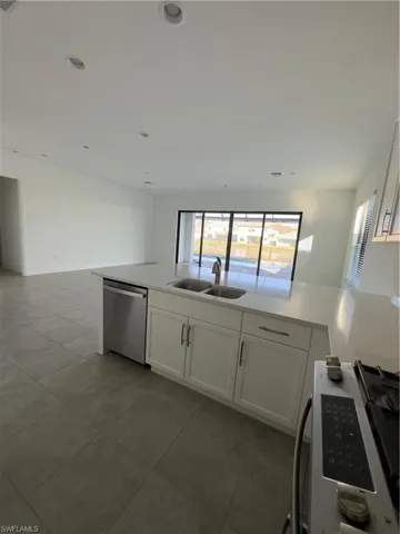 Kitchen featuring open floor plan, white cabinets, dishwasher, a peninsula, and plenty of natural light
