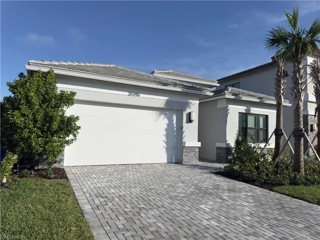 View of front of property with stone siding, decorative driveway, stucco siding, and a garage