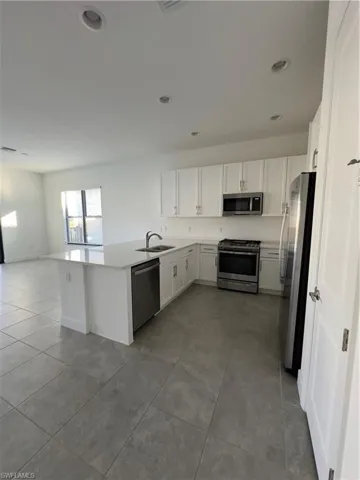 Kitchen featuring stainless steel range oven, white cabinets, refrigerator, dishwasher, and open floor plan