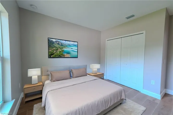 Bedroom with wood finish floors, a closet, visible vents, and baseboards