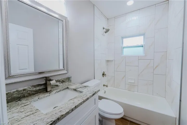 Bathroom featuring vanity, toilet, recessed lighting, and  shower combination