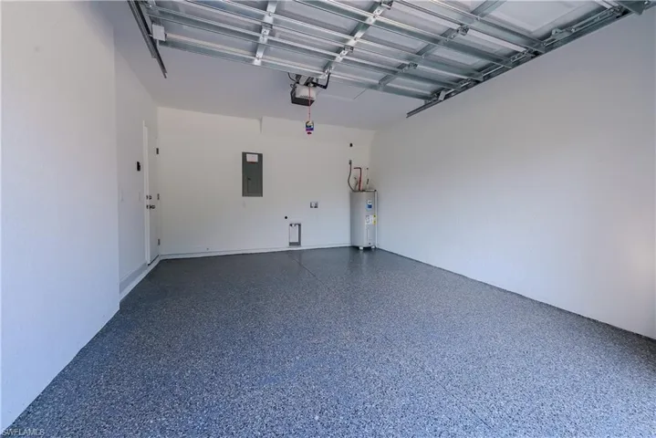 Garage featuring a garage door opener, water heater, and electric panel