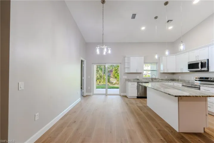 Kitchen with white cabinetry, a sink, appliances with stainless steel finishes, visible vents, and a high ceiling