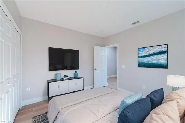 Bedroom with visible vents, light wood-type flooring, and baseboards