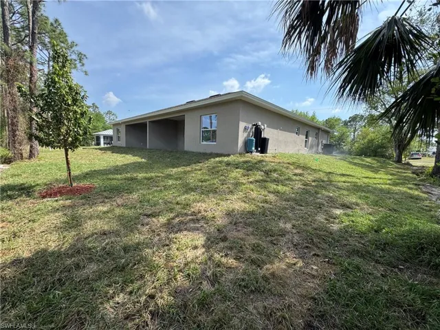 View of home's exterior featuring a lawn, stucco siding, and a carport