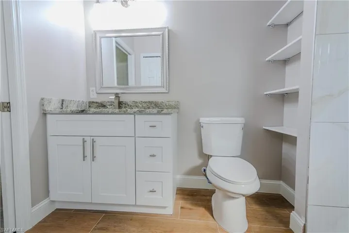 Bathroom with toilet, wood finished floors, vanity, and baseboards