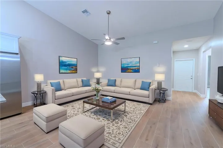 Living area with baseboards, visible vents, a ceiling fan, and light wood finished floors