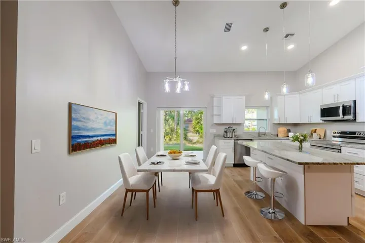 Kitchen with a towering ceiling, visible vents, stainless steel appliances, and white cabinets