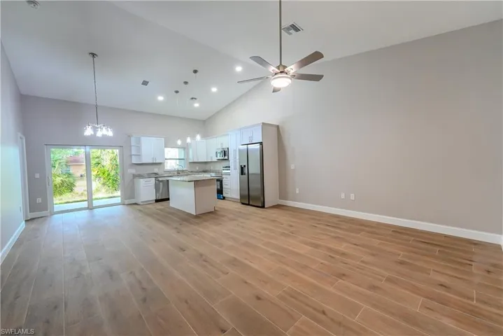 Kitchen with appliances with stainless steel finishes, open floor plan, a kitchen island, and high vaulted ceiling