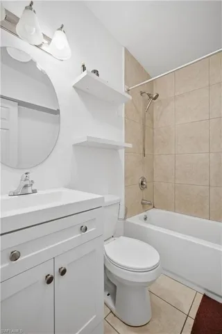 Bathroom featuring a white vanity with integrated sink, chrome faucet, and round mirror