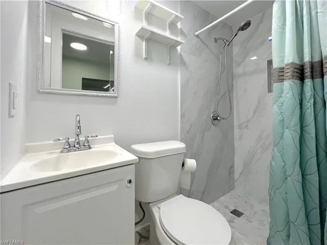 Compact bathroom featuring a corner vanity with a single basin sink and chrome faucet