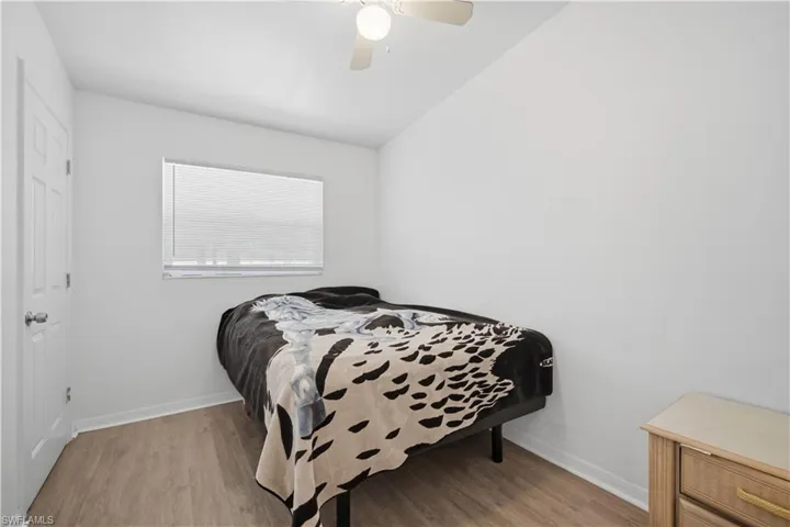 Bedroom featuring light wood-finish flooring, white walls, and a window with blinds