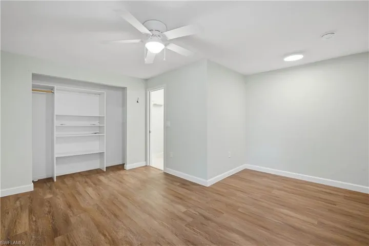 Room featuring wood-finish flooring, a ceiling fan with integrated lighting, recessed overhead lighting, and white baseboards