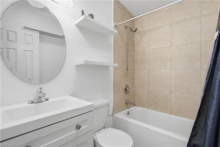 Bathroom featuring a white vanity with integrated sink, chrome faucet, and round wall mirror